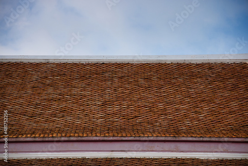 A perfectly tiled roof on a Buddhist temple in Asia. You can see the orange bricks and the cloudy sky very well!