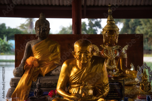 Three beautiful golden Buddha statues sitting and meditating outside in front of a temple in Hua Hin Thailand.