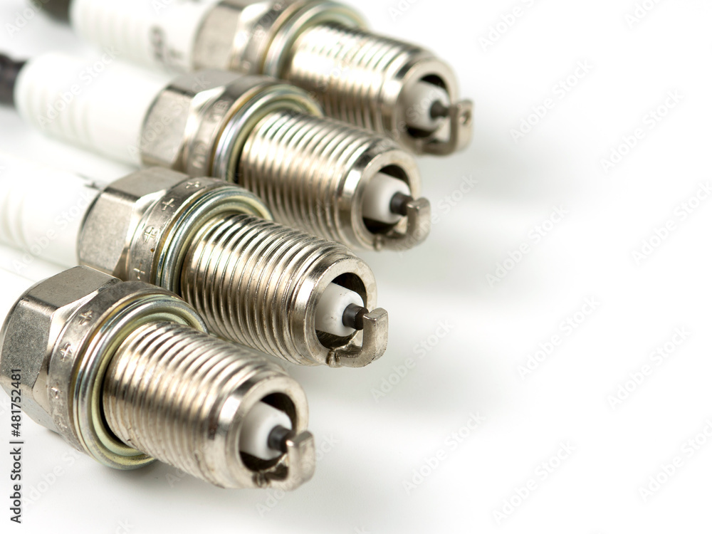 New spark plug on a white background, isolated. Group of four spark plugs for an automobile motor close-up New spark plug on a white background, isolated. Group of four spark plugs for an automobile motor close-up
