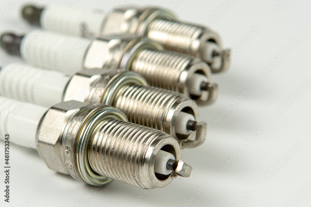 Car service. A set of new car spark plugs as a spare part of motor vehicles on white. Group of candles for the motor close-up Car service. A set of new car spark plugs as a spare part of motor vehicles on white. Group of candles for the motor close-up