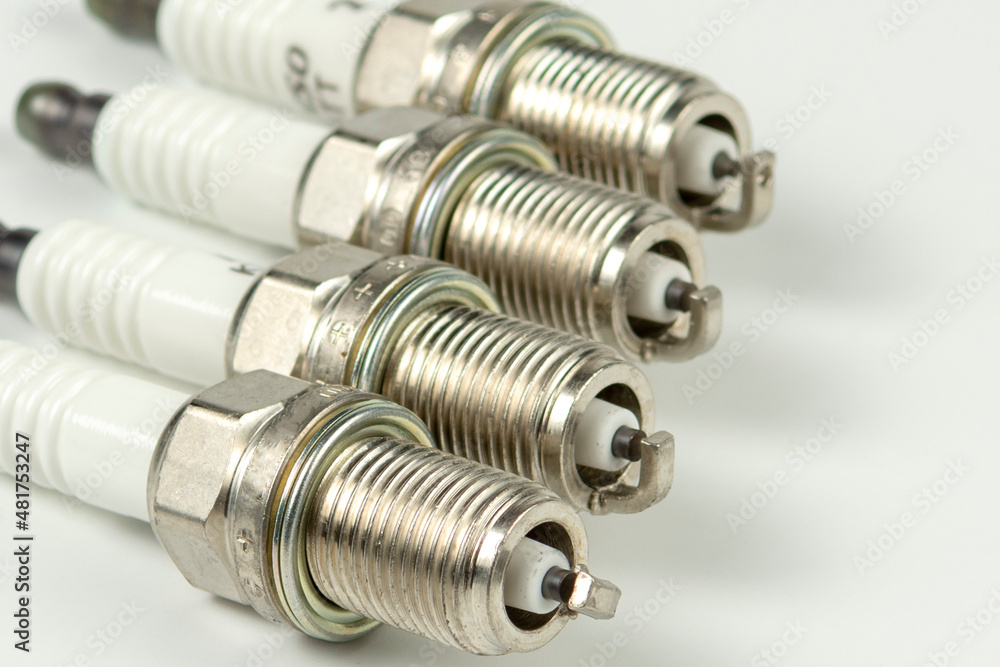 Car service. A set of new car spark plugs as a spare part of motor vehicles on white. Group of candles for the motor close-up Car service. A set of new car spark plugs as a spare part of motor vehicles on white. Group of candles for the motor close-up