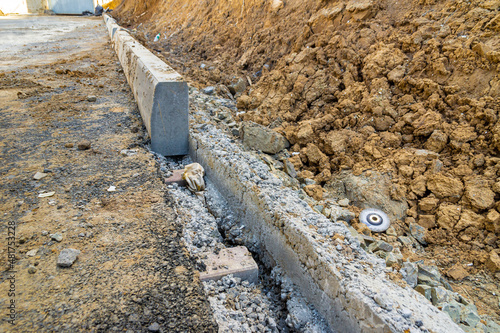 Installation of a curbstone along the edge of a new road, in a residential area under construction
