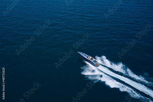Boat performance drone view. Performance speedboat moving fast on blue water aerial view. Dark gray blue boat in motion at sea. photo