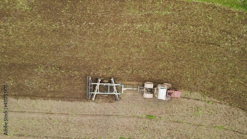 Aerial view of tractor plowing agriculural farm field preparing soil for seeding in summer photo