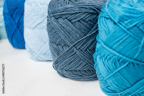 Craft hobby with wood yarn ball on white background, still life photo with soft focus. View from side. Handicraft day concept. Place for text. Woolen ball Crochet background blue Pastel theme.