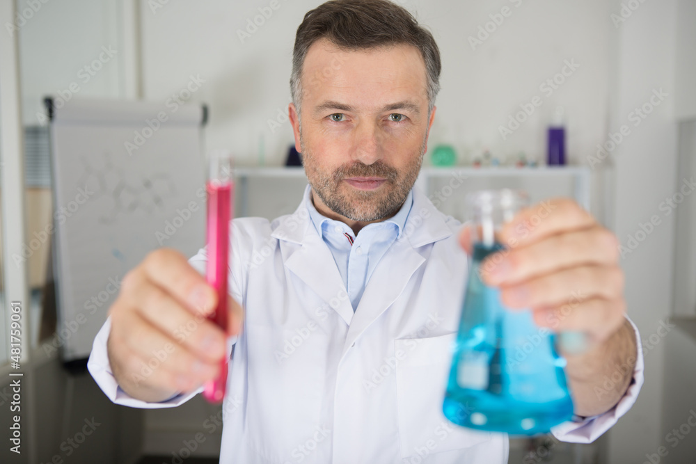 doctor in medical gown examines liquid in flask doctor in medical gown examines liquid in flask