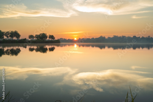 Trees and white clouds on blue sky with reflective in the water.Natural landscape in the morning time. © arcyto