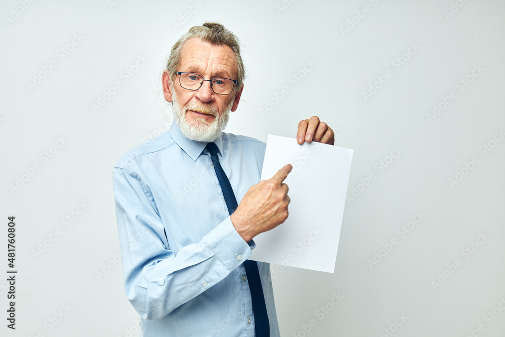 Senior grey-haired man holding documents with a sheet of paper light background Senior grey-haired man holding documents with a sheet of paper light background
