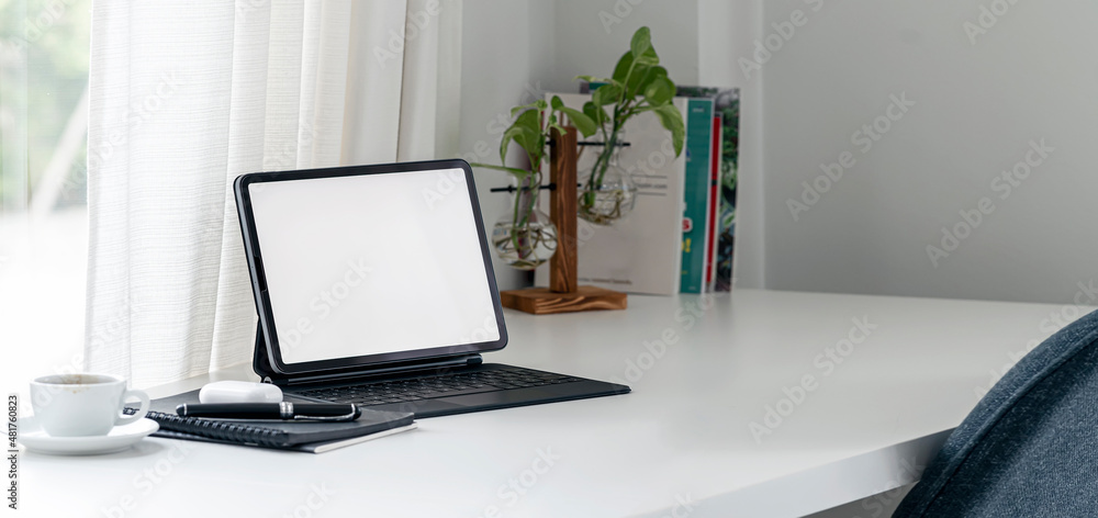 A simple workspace at home with portable tablet and keyboard on white table. A simple workspace at home with portable tablet and keyboard on white table.