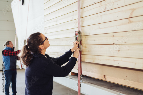 Obraz na plátně Factory worker tightening a ratchet strap on prefabricated walls