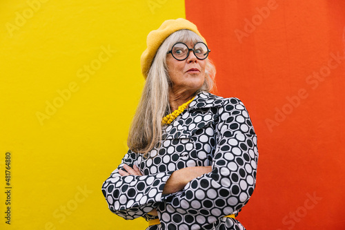Foto Senior woman looking surprised while standing against a colourful wall