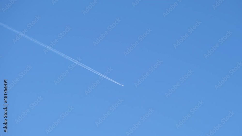 Distant passenger jet plane flying on high altitude on clear blue sky leaving white smoke trace of contrail behind. Air transportation concept Distant passenger jet plane flying on high altitude on clear blue sky leaving white smoke trace of contrail behind. Air transportation concept