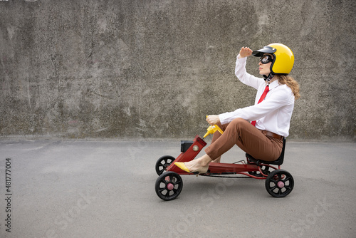 Funny businesswoman driving retro pedal car outdoor
