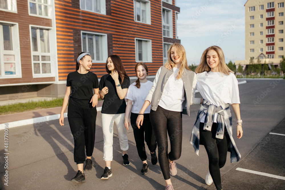 Fototapeta premium Group of young happy girls is walking around the city, having fun and laughing. Concept of relaxation and girly friendship