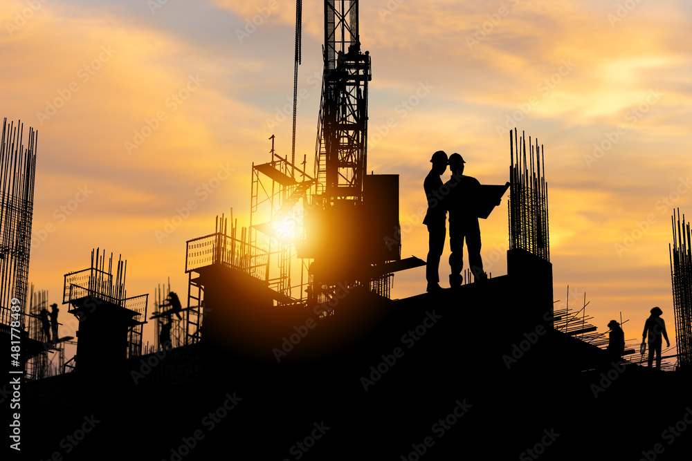 Silhouette of Engineer and worker team on building site, construction site with sunset in evening time
