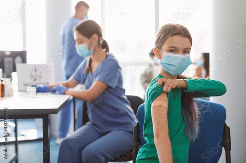 Teenage Lady Showing Vaccinated Arm With Adhesive Bandage In Clinic photo