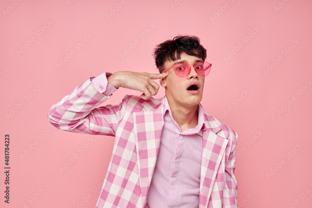 A young man fashionable pink sunglasses jacket posing isolated background unaltered A young man fashionable pink sunglasses jacket posing isolated background unaltered