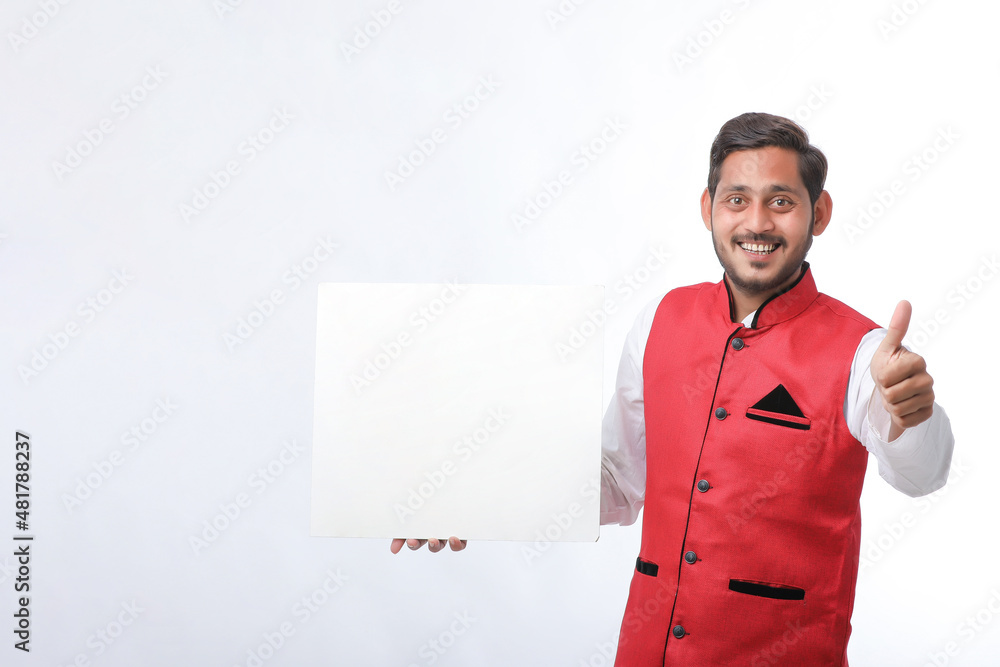 Indian man holding white board, promoting offers on festival season while wearing traditional cloths, standing over white background. Indian man holding white board, promoting offers on festival season while wearing traditional cloths, standing over white background.