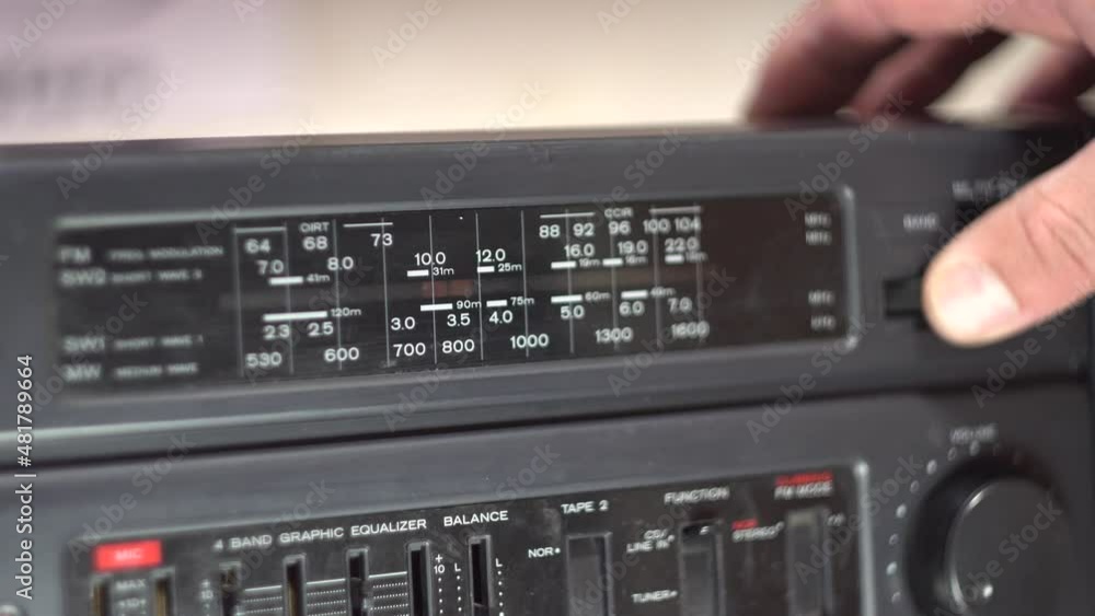 The scale of radio waves on a cassette recorder. Setting up a radio station. Finger. Dark body. Retro electronics. Old fashioned design. Analog control. Close-up. The scale of radio waves on a cassette recorder. Setting up a radio station. Finger. Dark body. Retro electronics. Old fashioned design. Analog control. Close-up.