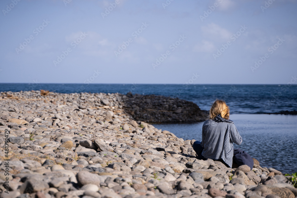 Young blonde woman sitting looking at the sea Young blonde woman sitting looking at the sea