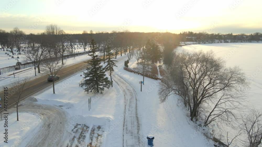 Aerial view of a park covered in snow during a winter sunset with cars driving by, in Minneapolis Aerial view of a park covered in snow during a winter sunset with cars driving by, in Minneapolis