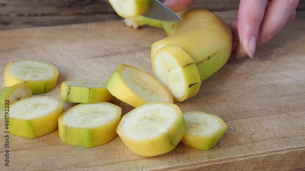 The banana in the peel is cut into slices on a cutting board. Close-up. Unpeeled banana slices. The banana in the peel is cut into slices on a cutting board. Close-up. Unpeeled banana slices.