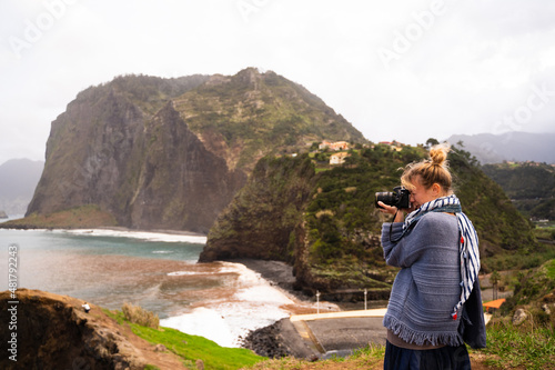 Woman standing taking photos with a digital camera of the sea from a view point