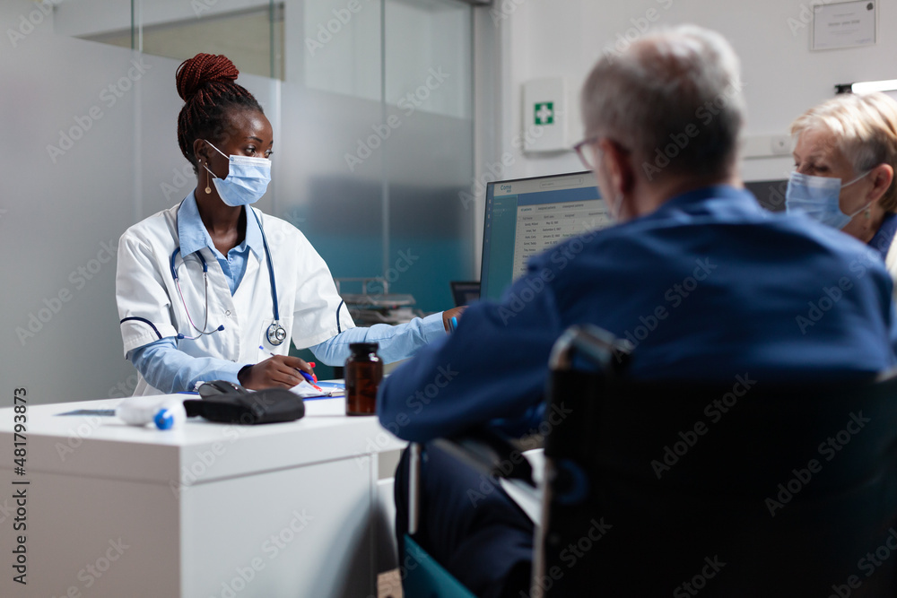 Fototapeta premium Physician doctor wearing medical face mask to prevent infection with coronavirus in hospital office. Therapist woman explaining disease diagnosis to elderly people discussing healthcare treatment