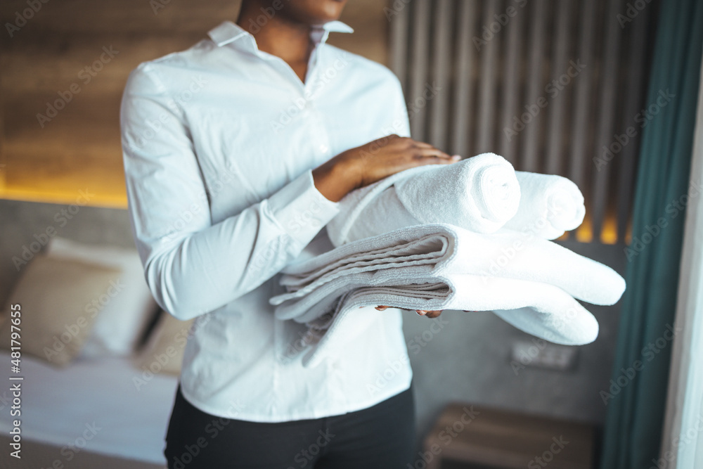 Maid with fresh clean towels during housekeeping in a hotel room. Maid