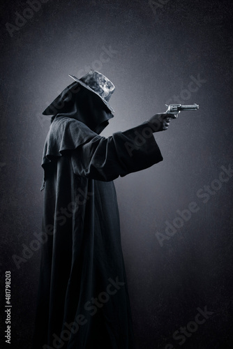Creepy figure with old hat and gun in the dark