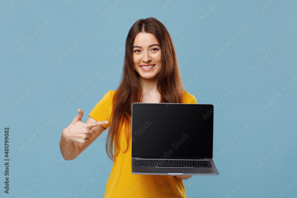 Happy young lady pointing at notebook with empty screen, mockup Happy young lady pointing at notebook with empty screen, mockup