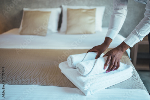 Change of towels in the hotel room. A uniformed maid is cleaning up the hotel room. Towels in the hands of the maid. The concept of the hotel business. Photos in the interior.