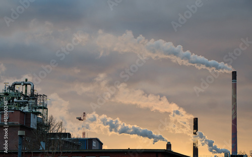 Schornsteine rauchen und verpesten die Luft im Industriezentrum Höchst bei Frankfurt am Main (Deutschland) im Sonnenuntergang