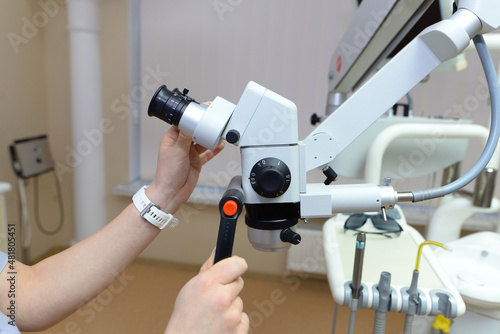 Modern dental clinic with a microscope to treat patients. Doctor's hands hold a medical microscope. Dentist man uses a microscope.