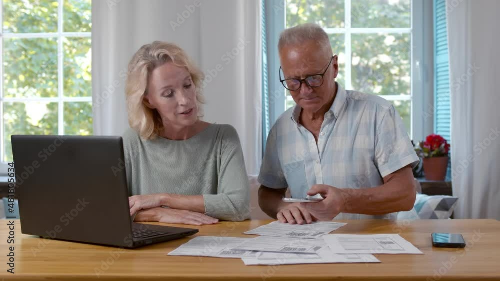 Senior man and woman scan qr-code and pay bills online sitting at home. Realtime. Senior man and woman scan qr-code and pay bills online sitting at home. Realtime.