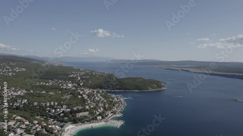 Video with Front Plane Drone advancing over the coast of Jadranovo in Croatia, clear sky with some clouds, you can see a pier with boats on the shore. photo