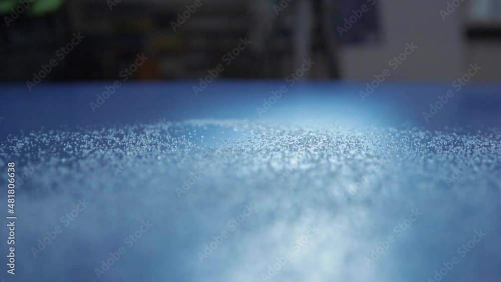 Sugar grains spilling towards camera over blue counter Sugar grains spilling towards camera over blue counter