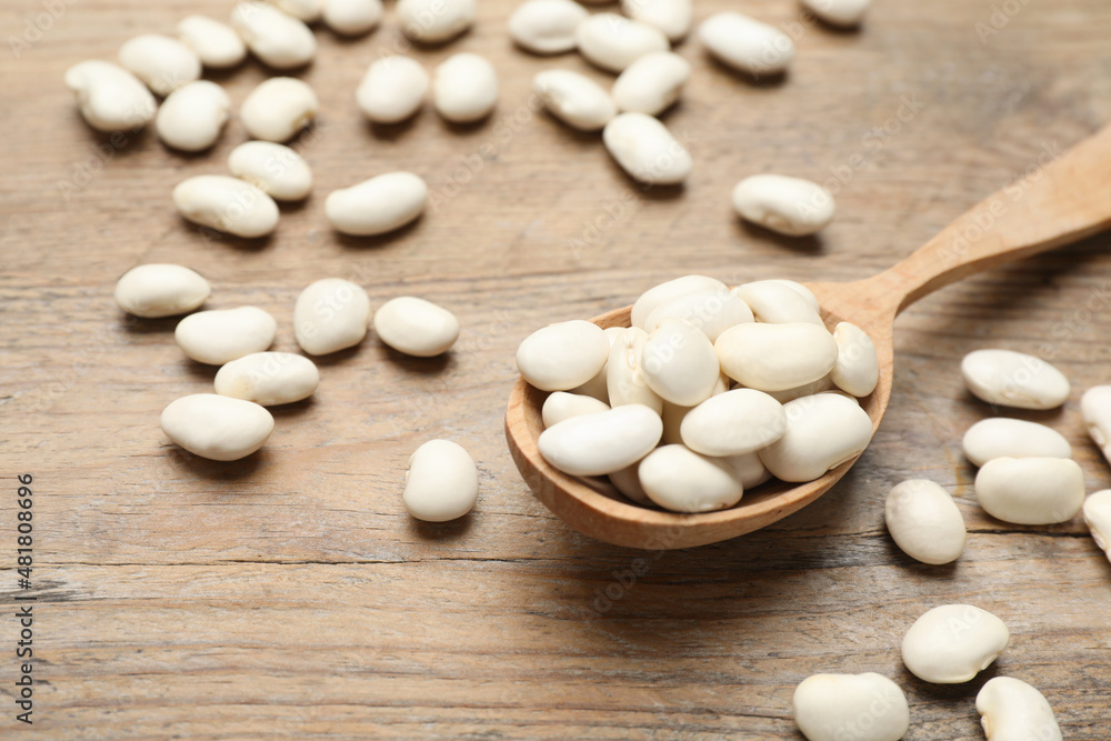 Raw white beans with spoon on wooden table, closeup Raw white beans with spoon on wooden table, closeup