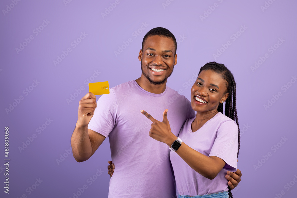 Happy afro couple holding and pointing credit card
