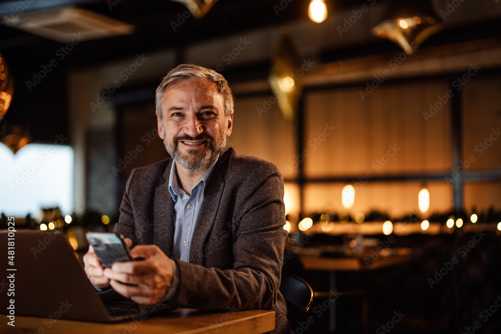 Portrait of smiling caucasian man, typing on his phone and smili