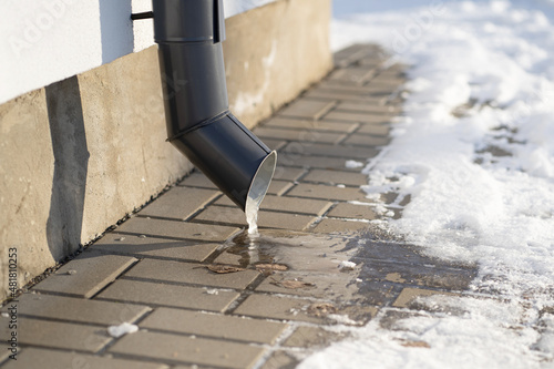 Icicle on the drain pipe. Ggray drainpipe owith frozen water on a private house. photo