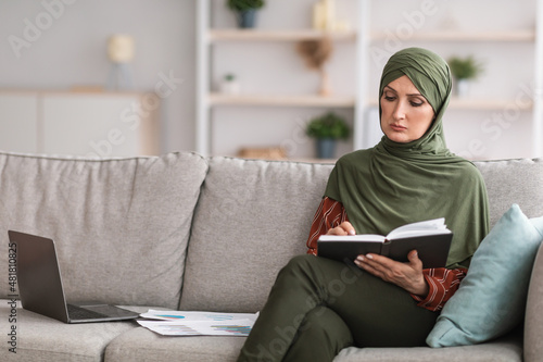 Modern Muslim Businesswoman Reading Notebook With Work Schedule Indoor
