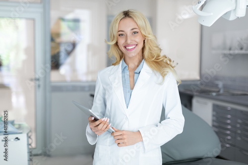 Beautiful woman dentist with digital tablet smiling at camera