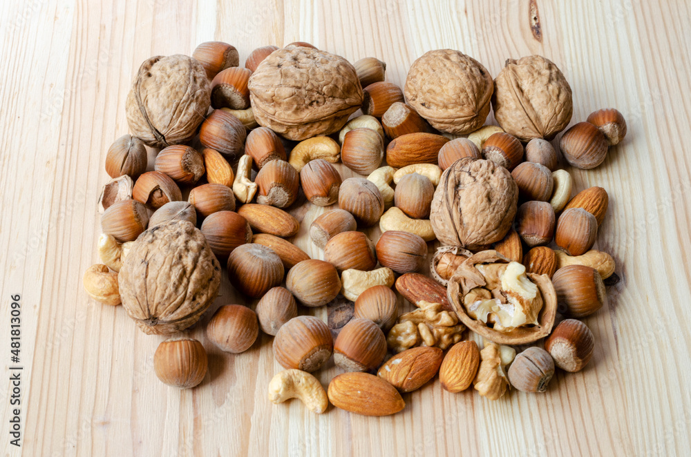 Mixture of walnuts, hazelnuts in shell almonds, cashews on a wooden table Mixture of walnuts, hazelnuts in shell almonds, cashews on a wooden table