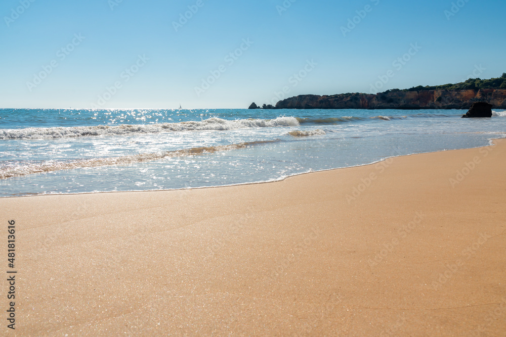view from the sandy beach of Alvor beach in Algarve, Portugal on a sunny day - water shine.