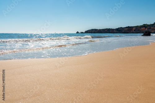 view from the sandy beach of Alvor beach in Algarve, Portugal on a sunny day - water shine.