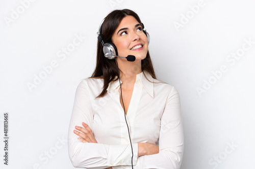 Telemarketer caucasian woman working with a headset isolated on white background looking up while smiling photo