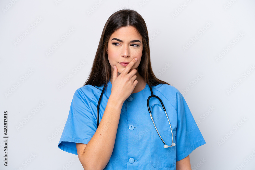 Young Brazilian nurse woman isolated on white background having doubts and with confuse face expression Young Brazilian nurse woman isolated on white background having doubts and with confuse face expression