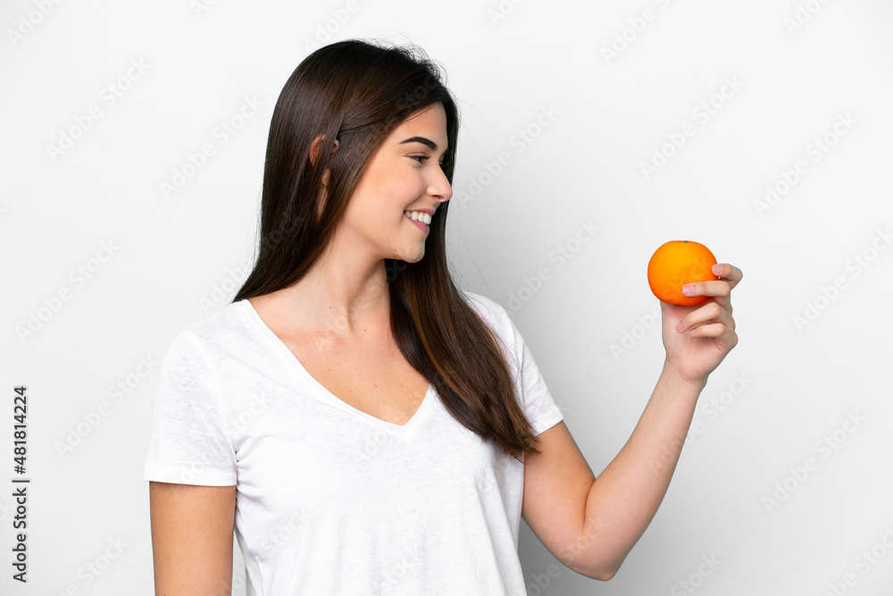 Young Brazilian woman holding an orange isolated on white background with happy expression Young Brazilian woman holding an orange isolated on white background with happy expression