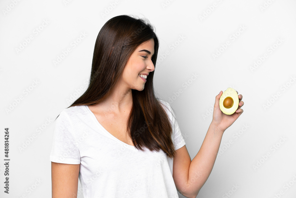 Young Brazilian woman holding an avocado isolated on white background with happy expression Young Brazilian woman holding an avocado isolated on white background with happy expression